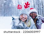 portrain of indian man and woman in red santa hat and deer horns with throwing snow on face