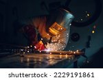 Man worker working with a metal product and welding it with a arc welding machine in a workshop. Industrial manufacturing. Welding metal part in a factory. Orange sparks. Copy space.