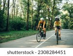 Smiling couple of riders cycling on racing bikes outside of the city. Active lifestyle and sport concept. Sporty couple of cyclist riding a bicycle on the road in the nature. Copy space.