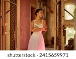 Small photo of A gracious prima ballerina is dancing her choreography in rustic place. A fragile ballet dancer is performing her choreography in abandoned place. A neon light outlines her devilish side. Copy space.