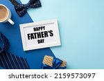 Small photo of Father's Day concept. Top view photo of white photo frame polka dot giftbox with blue ribbon bow cup of coffee bow-tie and necktie on bicolor blue background with copyspace