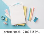 Small photo of Back to school concept. Top view photo of school supplies stack of notepads pens ruler stapler and adhesive tape on bicolor blue and white background with copyspace