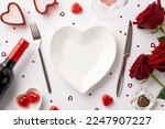 St Valentine's Day concept. Top view photo of heart shaped plate knife fork saucer with candies wine bottle glass candles bouquet of red roses and confetti on isolated white background with copyspace