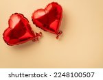 Valentine's Day concept. Top view photo of two heart shaped balloons on isolated pastel beige background with copyspace