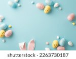 Easter party concept. Top view photo of easter bunny ears white pink blue and yellow eggs on isolated pastel blue background with copyspace in the middle
