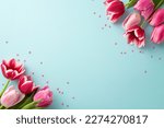 Mother's Day decorations concept. Top view photo of pink tulips and heart shaped sprinkles on isolated pastel blue background with copyspace