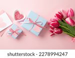 Mother's Day concept. Top view photo of blue gift boxes with ribbon bows bouquet of pink tulips heart shaped saucer with sprinkles and envelope with postcard on isolated pastel pink background