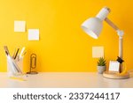Small photo of Schooltime creativity arrangement. Side view photo of pencil stand, ruler, clip shaped book holder, calendar, tiny academic hat, plant, lamp, sticky notes, yellow wall background. Space for text or ad