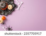 Small photo of Transform your Halloween table: Top view shot reveals cobweb shaped plate, pumpkins, spiders, bones, and confetti on lilac backdrop. Ample room for text or advert