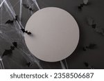 Small photo of Unsettling Halloween vision. Top view perspective photo of theme components: spiderweb and sinister creatures - bats. Dark setting with empty circle for text or promotion