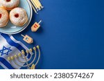 Small photo of Honor the Hanukkah season with a top-view photo featuring sufganiyot, Israeli flag, candles, and dreidel on a blue background, allowing for text or ad inclusion