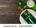 Small photo of Revel in St. Patric's Day spirit at the pub scene. Top view snapshot of a table adorned with plate, utensils, beer glass, leprechaun's gold, lucky horseshoe, trefoils, and beads on wooden surface