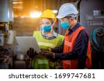 Portrait woman worker and engineer under inspection and checking production process on factory station by wearing safety mask to protect for pollution and virus in factory.