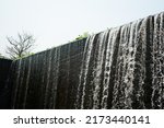 Small photo of Place is the flowing water like a small waterfall curtain. Water overflowing the mortar weir during the rainy season with tree and isolate white background at Pang Sawan Weir, Uthai Thani, Thailand.