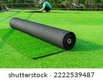 Small photo of Roll of an artificial turf laying background. A synthenic grass layer. Greenering of the yard of , green lawn background with workers pave the counterfeit grass.