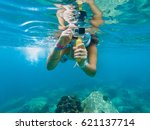 A young caucasian woman taking pictures under water.  Koh Tao, Thailand.