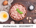 Raw minced meat in bowl on wooden table and ingredients. Ground meat with ingredients for cooking on dark background with copy space. Top view or flat lay