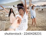 Small photo of Multiethnic group of young women dancing at chiringuito beach during sunset. The friends soak up the sunshine and music. Spirit of youthful exuberance and unbridled happiness concept