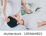 cropped shot of peaceful young woman receiving reiki healing treatment on head and chest