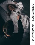 Small photo of exorcist holding cross over obsessed yelling girl in bed