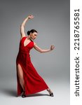 Woman in red dress and heels dancing on grey background