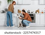 Small photo of Cheerful woman looking at husband with dalmatian dog in kitchen