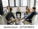 Multiethnic people with alcohol addiction sitting in circle in rehab center
