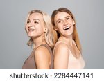 Cheerful women with skin issues standing back to back isolated on grey