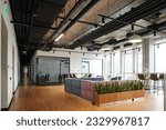 Small photo of spacious and contemporary office lounge with soft and comfortable couch, large windows, high chairs and green plants, workspace organization concept