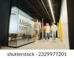motion blur of energetic and ambitious business people walking near meeting room in coworking environment of modern office with high tech interior, full length, dynamic business concept
