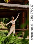 Small photo of summer park, indian woman in elegant ethnic wear dancing near wooden alcove in summer park