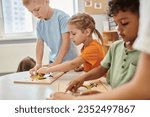 Small photo of interracial children playing with didactic materials on table in montessori school