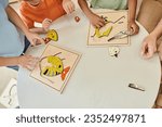 Small photo of top view, cropped interracial kids playing with didactic montessori material in school, puzzle