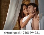 Small photo of romantic couple, beautiful woman seducing man in white clothes and sitting in private pavilion