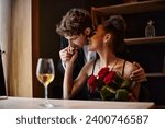 gentleman kissing hand of happy african american woman holding roses during date on Valentines day