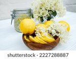 Small photo of Slices of fresh lemon in a wooden plate. Ingredients for herbal tea from elder syrup. Snappy ambucus stalks ready to make a cold summer drink