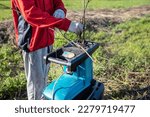 Small photo of electric garden grinder to shred. in the process. The gardener crushes the branches and makes fuel for the boiler from the remnants after pruning garden trees and vineyards