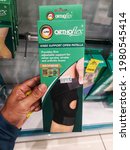 Small photo of Shah Alam, Malaysia - 21 May 2021 : Hand hold a boxed of LPM Knee Support Open Patella for sell in the Caring Pharmacy Shop in Shah Alam, Malaysia with selective focus.