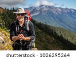 Hiker poses in front of mountain peaks range hiking backpacker old older aarp strong strength vital energetic landscape photography portrait background colorful adventure retired retirement outdoor 