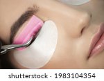 Master glues eyelashes to pink lash roller. Close-up of beauty model's face during lash lift laminating botox procedure. Eyelash Care Treatment: lifting and curling, lash lamination and extension.
