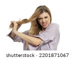 Young sad woman combs to her long wavy hair. Model with long curly hair angry combing her tangled hair.  Haircare beauty products, shampoo and lotion. Hair Care Spa and wellness