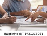 Small photo of financial investor advisory. Close up hand pointing at contract and document while sitting together with young couple at the desk in office