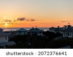 Small photo of Aerial view on colorful yellow sunset sun with ocean landscape of Gulf of Mexico in Seaside, Florida from rooftop terrace buildings houses cityscape and weather vanes
