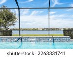 Modern contemporary home screened glass lanai private pool spa with view of tropical lake in Florida with blue water in clean house