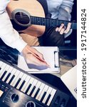 Small photo of male songwriter writing a song with laptop computer and keyboard on desk. songwriting concept