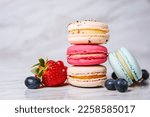 Macaron pink, orange and beige, blue on marble style. A beautiful and beautiful French dessert. Fruits, Strawberries and lingonberries, blueberries, raspberries