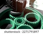 Small photo of Detail view on print head of 3D-printer making a planetary gear part from mint coloured plastic. selective focus. Visible infill structure and layers at printed part. Modern production concept