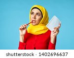 Small photo of Arab woman in a parser tends to handle in a hand with a notebook on a blue background