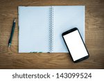 Pen and smartphone and notebook on wooden table