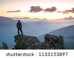 Young Man Standing on the edge of a cliff and enjoys the sunrise in southtyrol Italy